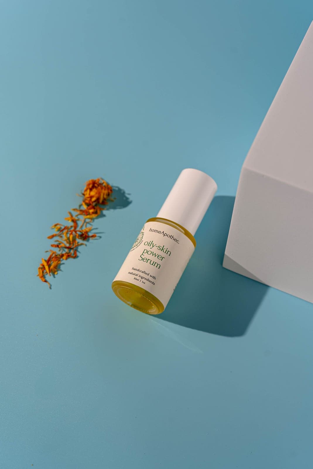 Oily Skin Power Serum lying beside dried calendula