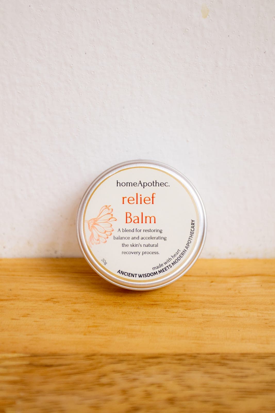A Relief Balm tin resting on a wooden shelf against a white wall